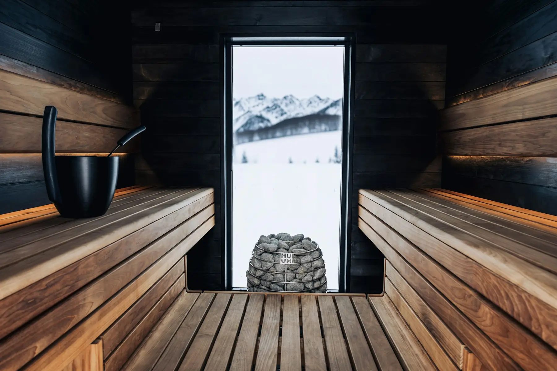 A dark wooden sauna with a window onto snow